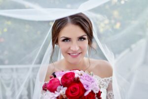 Beauty bride in bridal gown with bouquet and lace veil in the nature
