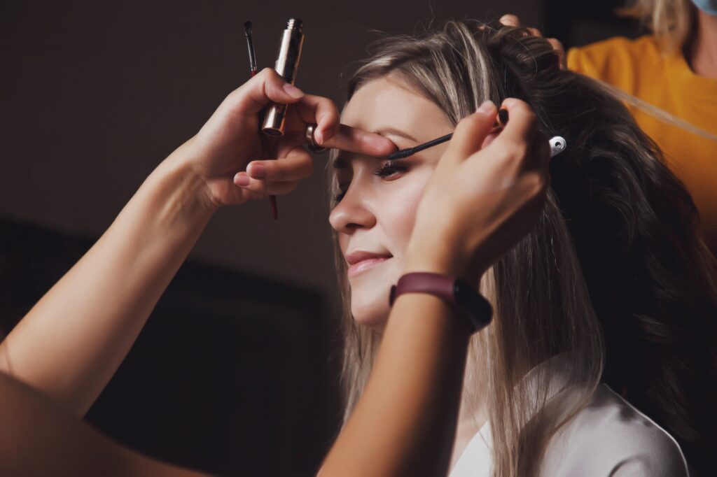 Makeup artist made wedding make-up for cute young woman bride at wedding day in hotel room